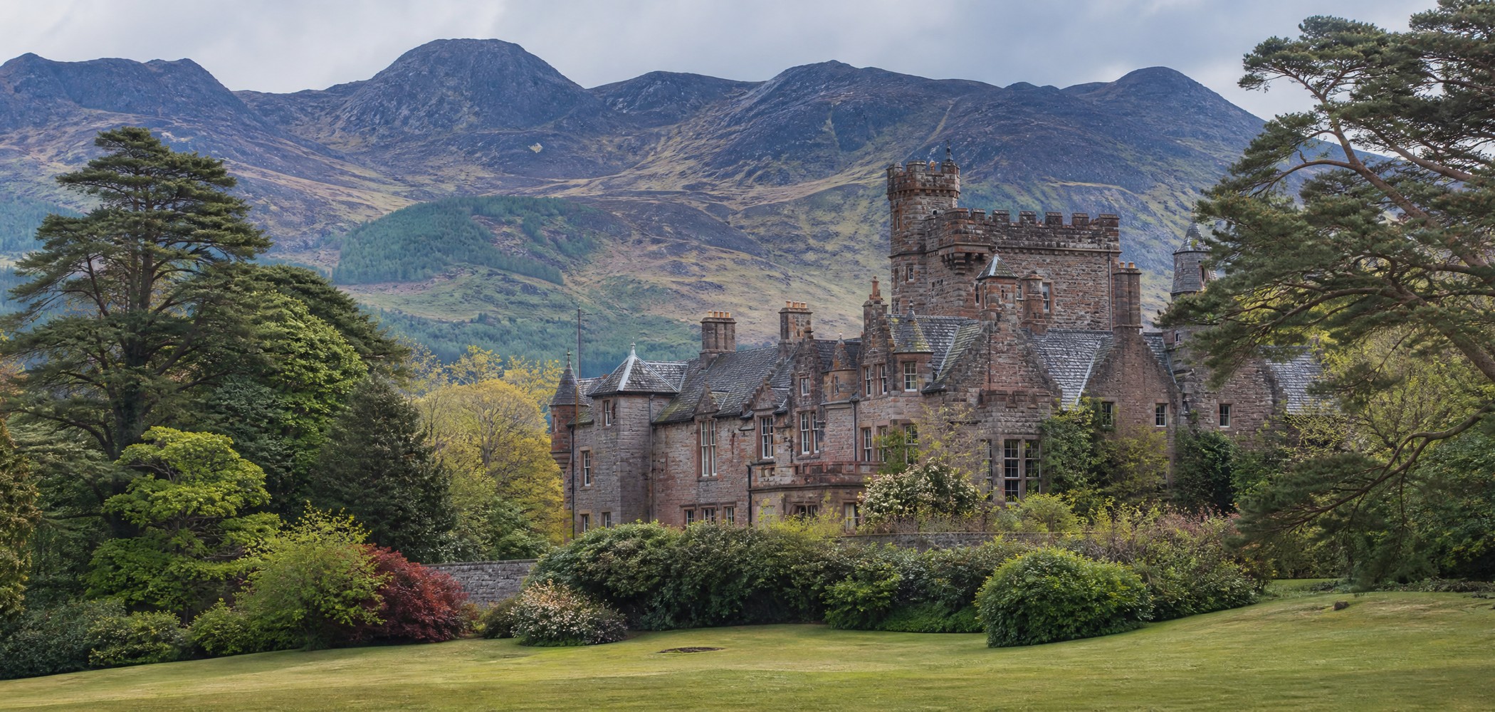 Brodick Castle framed by woodland and mountains on the Isle of Arran.