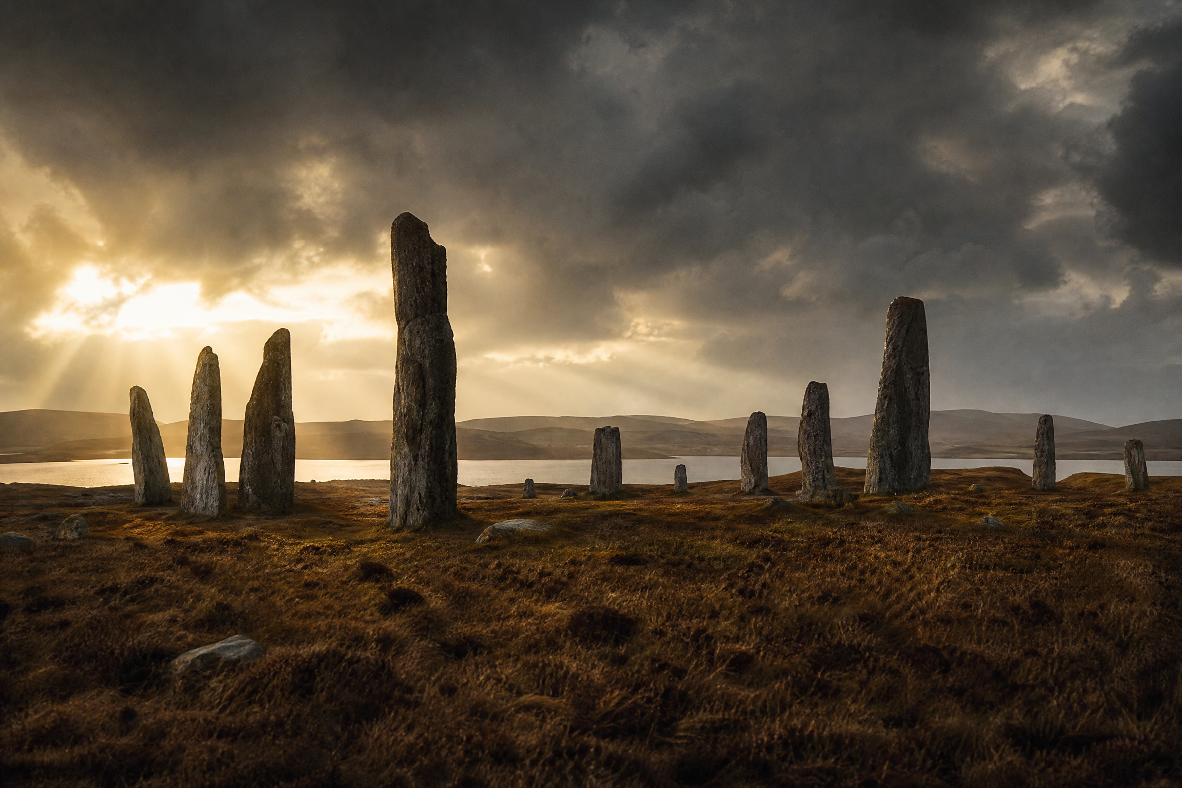 Callanish Standing Stones megalithic circle on the Isle of Lewis under a stormy sky with golden light, Scotland