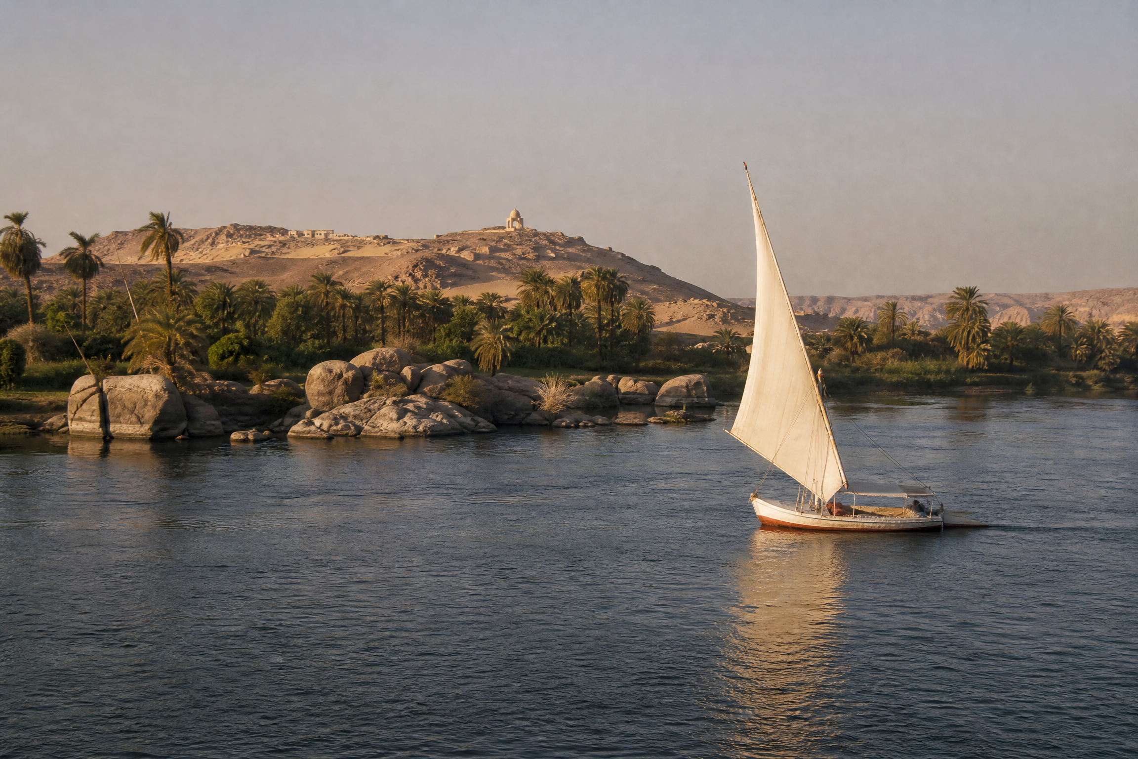 Traditional felucca sailing boat on the Nile River near Aswan with Elephantine Island in the background