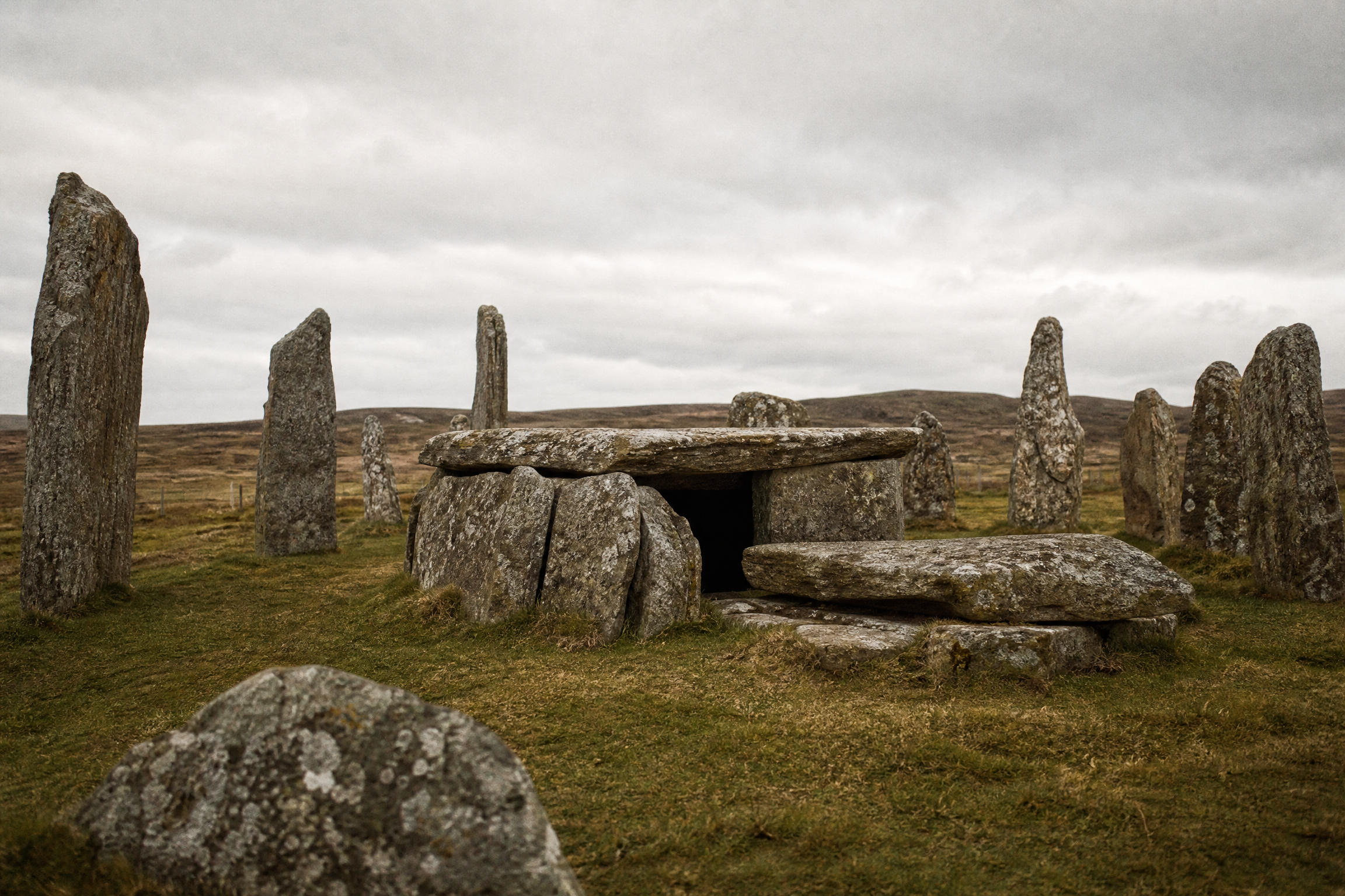 Neolithic chambered cairn tomb within the Callanish stone circle, showing flat capstones and upright stone slabs under overcast moorland light