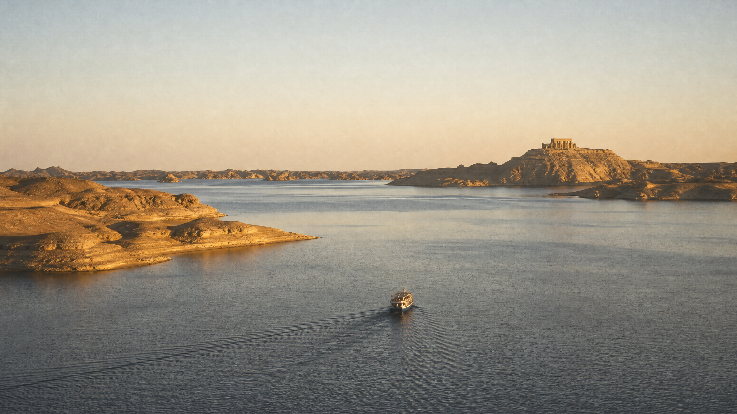 Small cruise vessel crossing the open water of Lake Nasser, flanked by Nubian desert headlands
