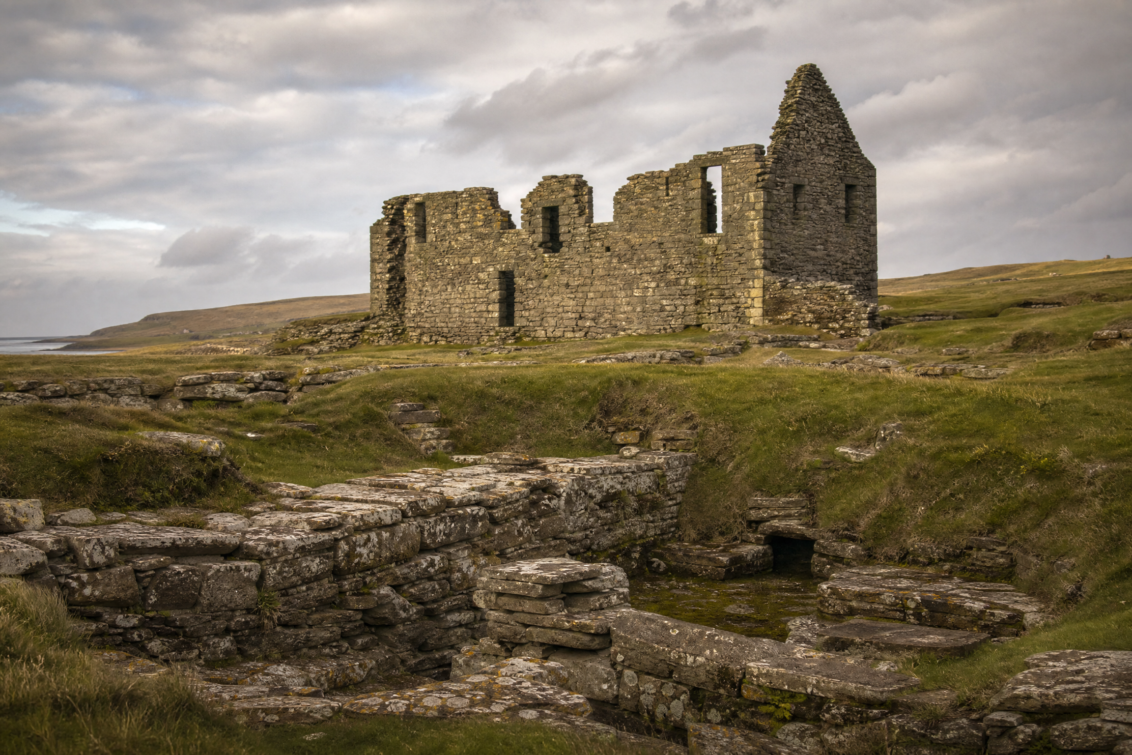 The roofless stone remains of the Old House of Sumburgh standing above earlier ruins at Jarlshof, Shetland