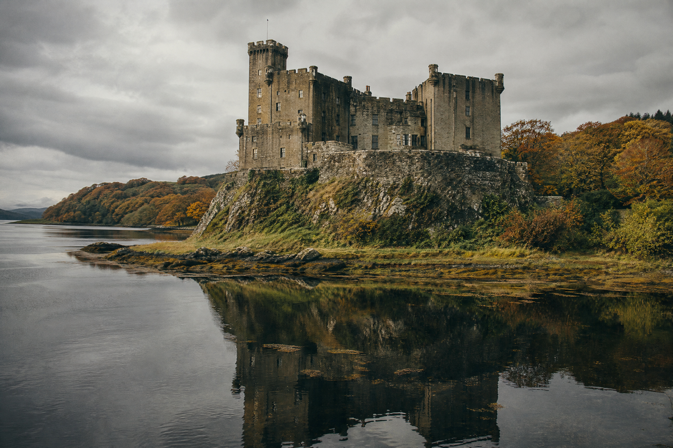 Dunvegan Castle on its rocky promontory, reflected in the still loch, Isle of Skye