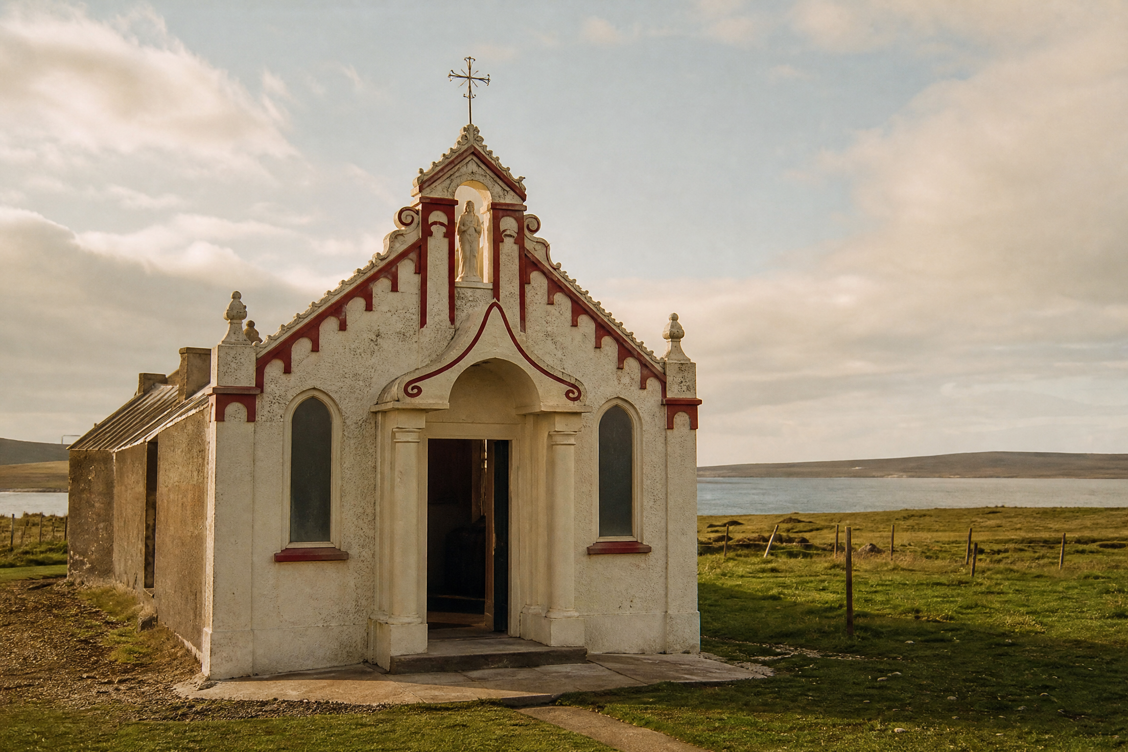 Ornate white and red facade of the Italian Chapel on Lamb Holm, Orkney, set against open island landscape