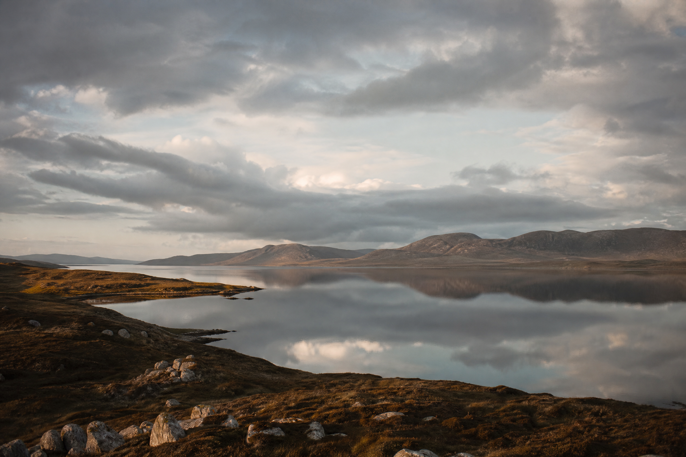 East Loch Roag reflecting the wide Hebridean sky and the hills of Harris, with moorland headlands lit in warm light