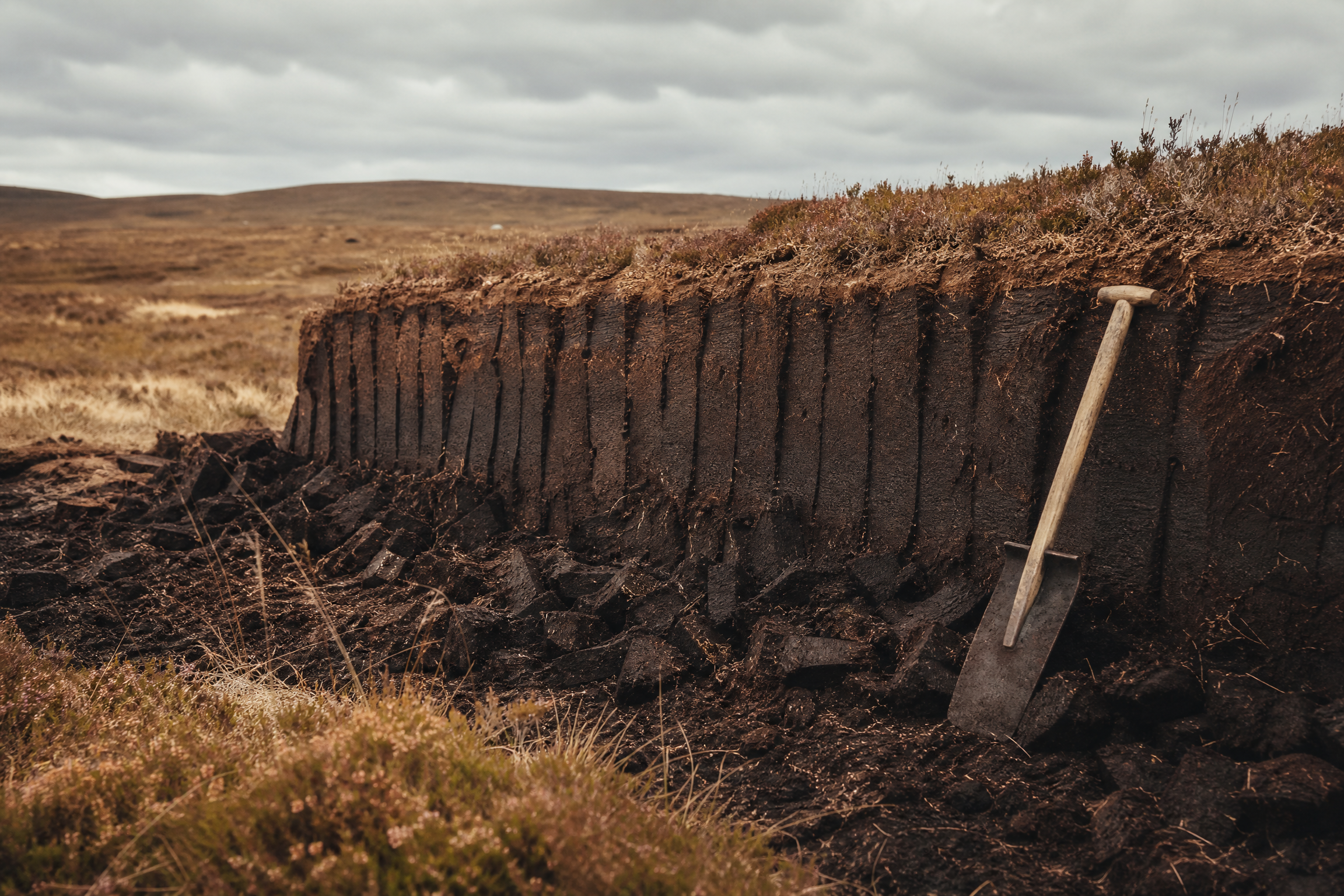 Peat cutting bank on Lewis with a traditional tarasgeir spade resting against a freshly sliced peat face