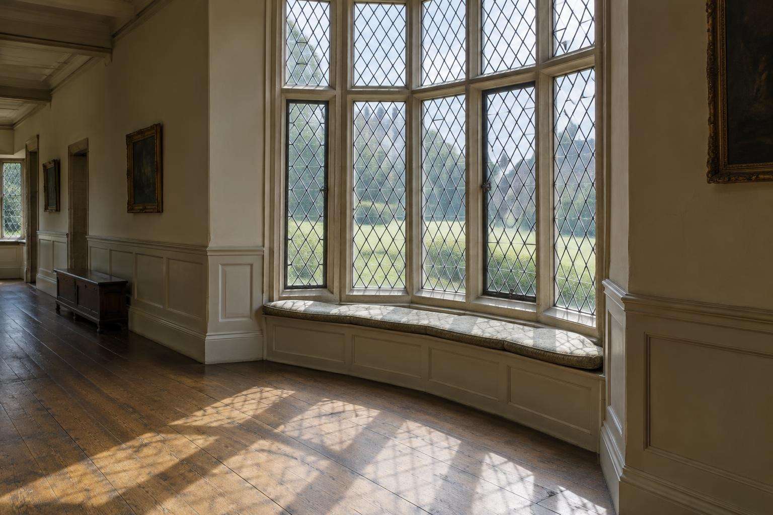Daylight falling through a leaded latticed bay window onto the floorboards of a country-house gallery in Wiltshire.