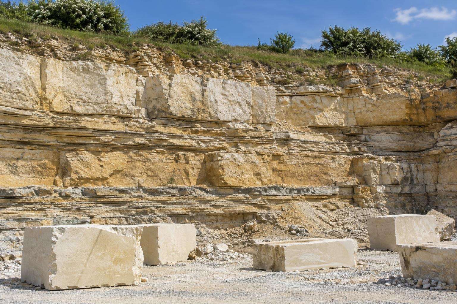 Layered beds of cream and golden oolitic limestone and freshly cut blocks in a Cotswold quarry, Gloucestershire.