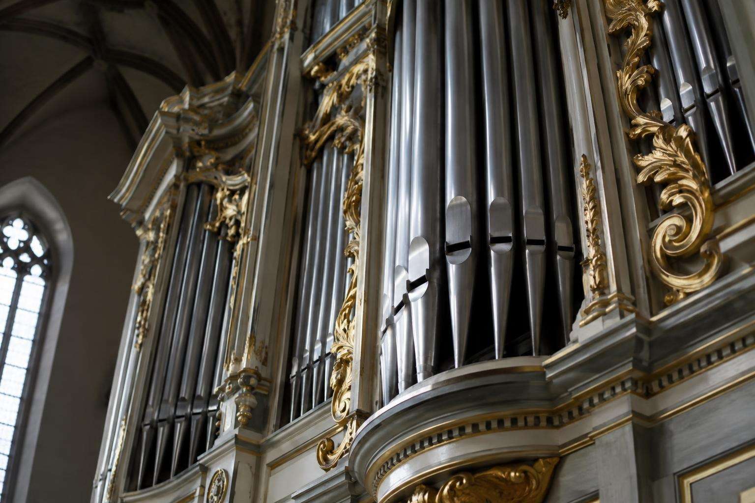 Close view of tin organ pipes and a carved, painted wooden organ case in a Lutheran church in Leipzig, Germany