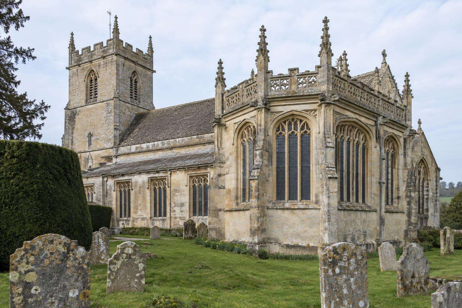 Perpendicular Gothic windows and carved parapet of a fifteenth-century limestone parish church in Wiltshire.
