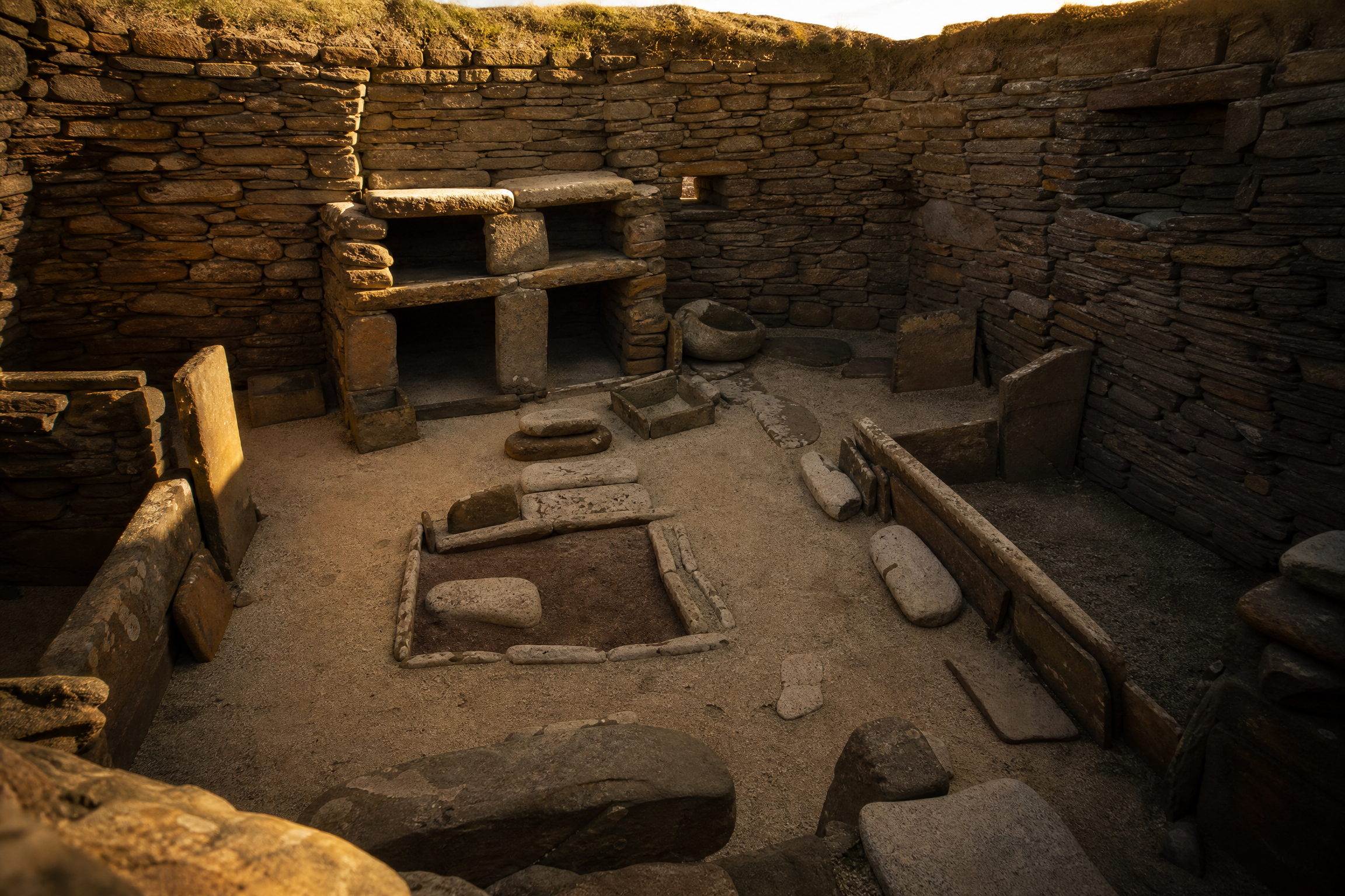 Interior of a preserved Neolithic house at Skara Brae, Orkney, showing a stone dresser, hearth and box beds