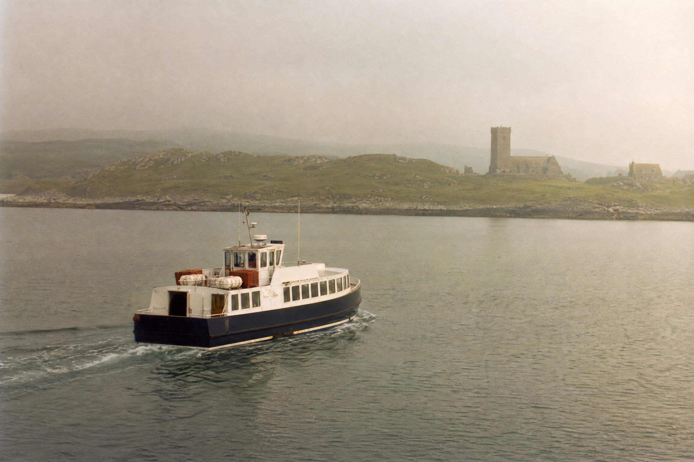 Passenger ferry crossing to Iona, with Iona Abbey tower visible in the misty distance