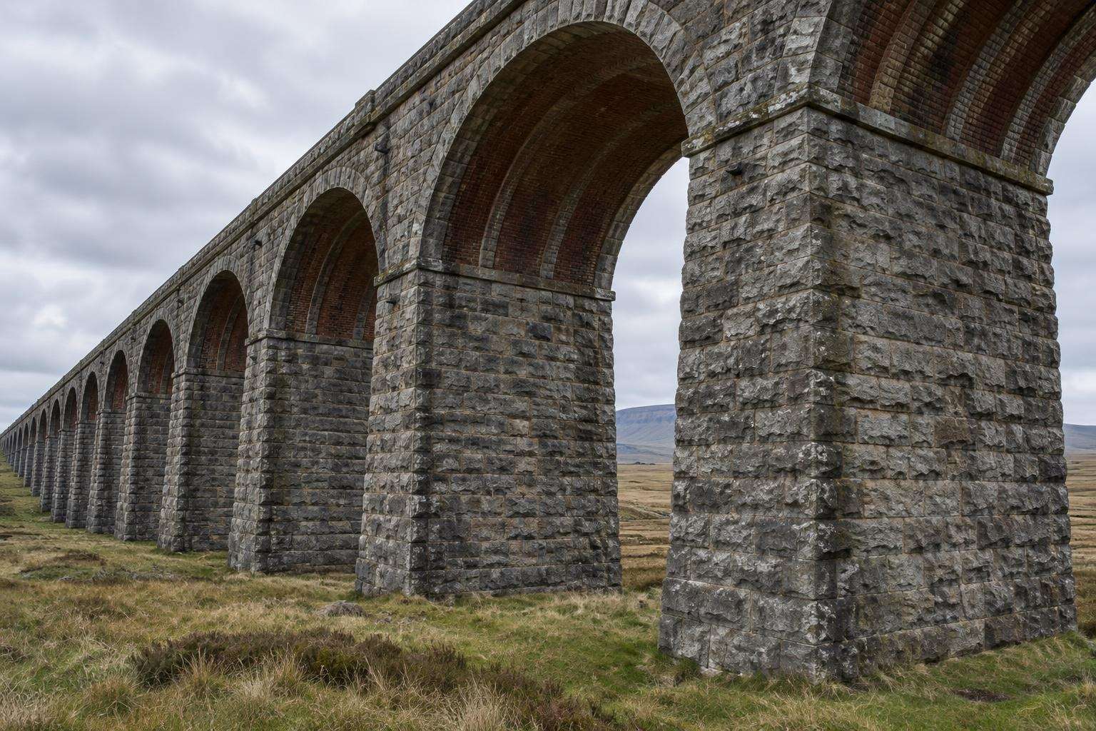 Looking along the limestone piers and brick-lined arches beneath the Ribblehead Viaduct, Yorkshire Dales, including one of the thicker piers